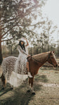 Bride riding a chestnut horse in a cowboy hat, star lace wedding dress draped over the saddle, Counting Stars