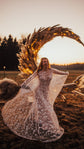 Bride laughing and twirling a sheer star lace wedding dress by a lit pampas grass arch at golden hour, Counting Stars
