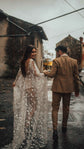 Bride looking back with a smile, open back star lace wedding dress with long sleeves on a village street, Counting Stars