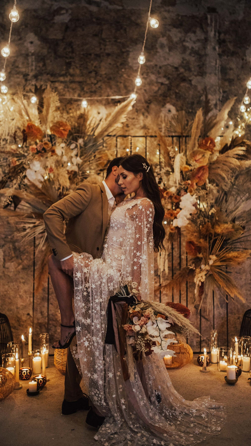Couple at a candlelit dried flower backdrop, bride in a sheer star lace wedding dress with sleeves draped long, Counting Stars