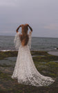Bride on a rocky shore with hands in her hair, open back star lace wedding dress and train behind her, Counting Stars