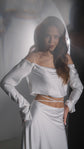 Off-shoulder silk satin crop top with long sleeves and a satin bridal skirt with waist ties, hand on hip, Danielle