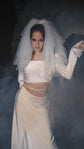 Bride in a puffed tulle veil and a two-piece satin wedding dress, crop top with long sleeves in studio haze, Danielle