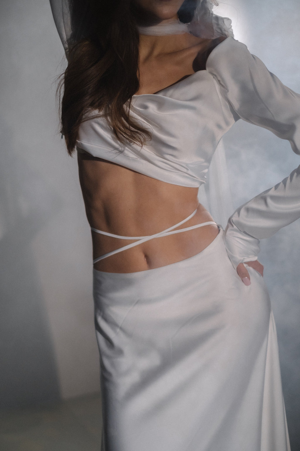 Close crop of a draped satin crop top and bridal skirt with thin ties crossing the bare waist, Danielle