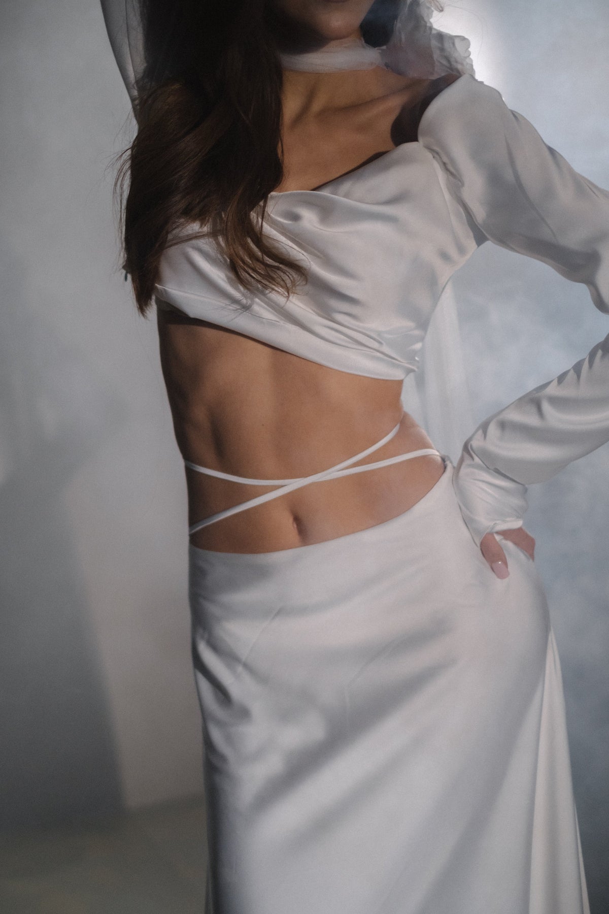 Close crop of a draped satin crop top and bridal skirt with thin ties crossing the bare waist, Danielle