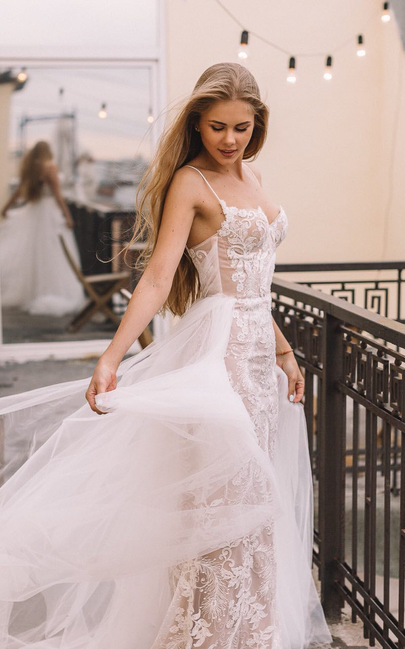 Bride swirling the tulle overskirt of a lace mermaid wedding dress on a rooftop with string lights, Feathers Sample