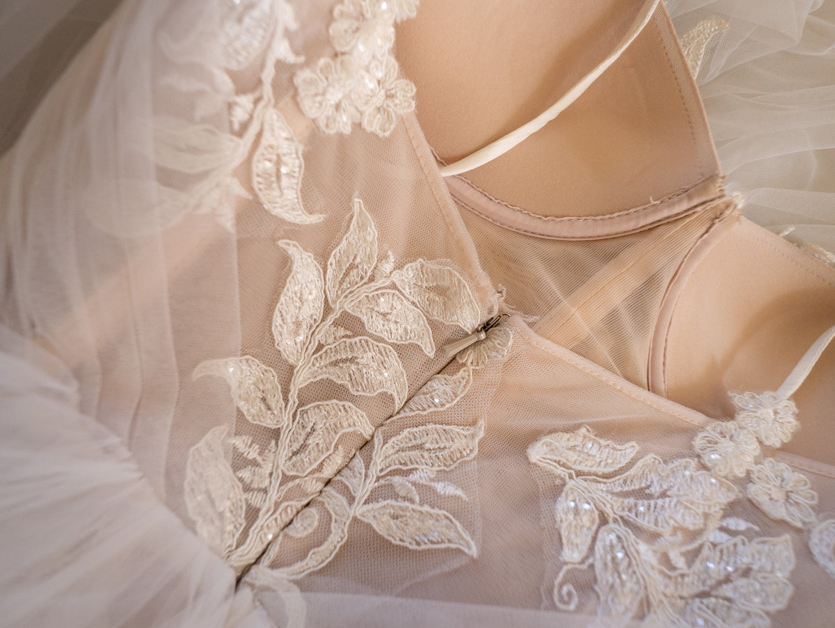 Close-up of lace leaves and sequin detail beside the structured cup of a wedding dress bodice, Feathers Sample