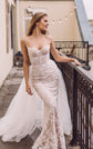 Bride on a rooftop terrace by a railing, fitted corded lace wedding dress with a full tulle overskirt, Feathers Sample