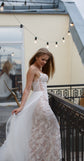 Bride looking down and holding out the tulle overskirt of a lace mermaid wedding dress, terrace lights, Feathers Sample