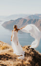 Bride holding a chiffon bridal sleeve out wide in the wind on a hilltop above a lake, FEYRE Sleeves