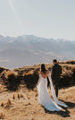 Back view of a couple walking into the hills, open back silk wedding dress and chiffon sleeves trailing, FEYRE
