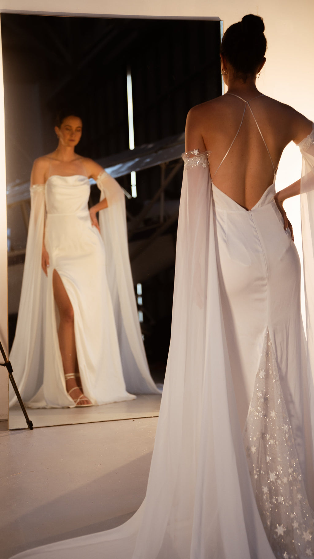 Bride by a mirror showing the cowl front and leg slit, back view with criss-cross straps and star lace panel, FEYRE