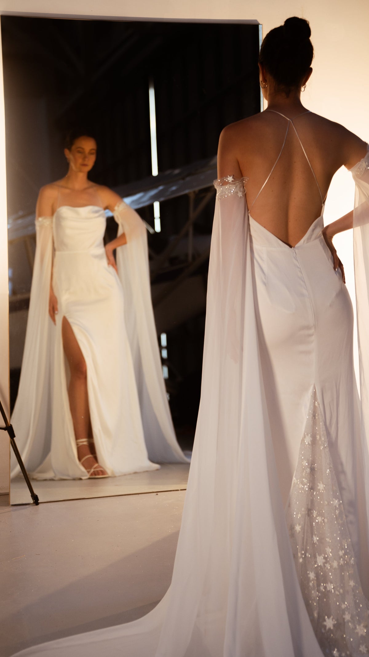 Bride by a mirror showing the cowl front and leg slit, back view with criss-cross straps and star lace panel, FEYRE