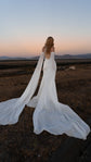 Back view of a bride at sunset on open grassland, open back silk wedding dress and long chiffon sleeve trains, FEYRE