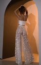 Back view of wide-leg star lace bridal pants and a strapless crop top, hands in hair against warm light, Galactic Outlaw