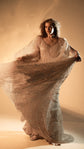 Two-piece celestial wedding dress in champagne glitter lace, model spreading the sheer flowing sleeves in warm studio light. Galaxy Champagne 2.0 by Ephemeris