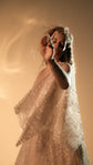 Model reaching toward the camera, slit sleeve of a glittering champagne lace wedding dress floating around the arm, Galaxy Champagne 2.0