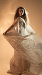 Model turning with a wide sheer sleeve lifted, champagne glitter lace wedding dress catching the amber light, Galaxy Champagne 2.0