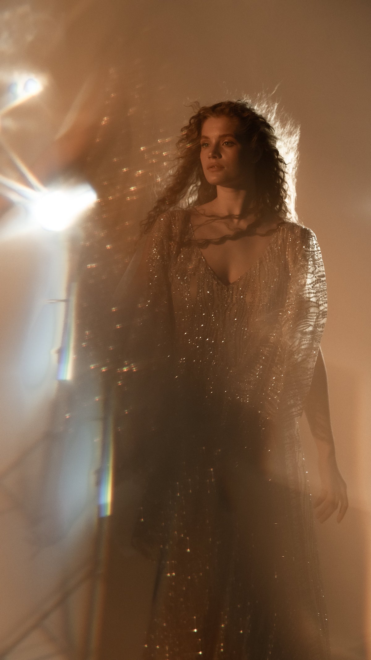 Hazy studio shot with a lens flare, sparkling beige lace wedding dress with draped sleeves, model gazing to the side, Galaxy Champagne 2.0