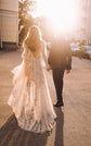 Back view of a low V-back champagne lace wedding dress backlit by the sun as the couple walks down a city street, Galaxy Champagne