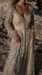 Cropped front view of a glitter-bright champagne lace wedding dress with sheer bishop sleeves against sunlit rock, Galaxy Champagne