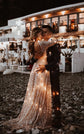 Open-back champagne lace wedding dress wrapped in fairy lights as the couple embraces on a pebble beach at night, Galaxy Champagne