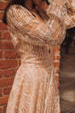 Detail of wavy glitter lace on the bodice and gathered sleeve of a champagne wedding dress against red brick, Galaxy Champagne
