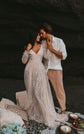 Couple in a beach cave with cushions and blue hydrangeas, bride in a V-neck ivory glitter lace wedding dress, Galaxy Ivory Sample
