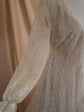 Close-up of a sheer glitter lace sleeve with a gathered cuff and the V-neck bodice of an ivory wedding dress, Galaxy Ivory Sample