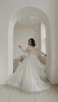 Back view of a bride dancing in a white archway, buttoned back of an ivory lace wedding dress and a wide swirling skirt, Galaxy Ivory
