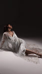 Model reclining on the floor in an ivory slip dress under a star embellished tulle robe spread around her, Infinity Slip Ivory