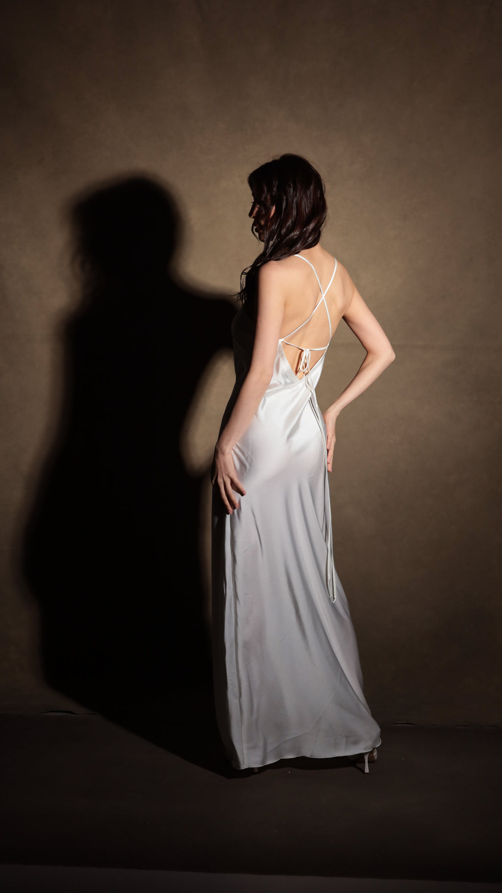 Full-length back view of an ivory bridal slip dress with criss-cross straps and a tie at the low back, Infinity Slip Ivory
