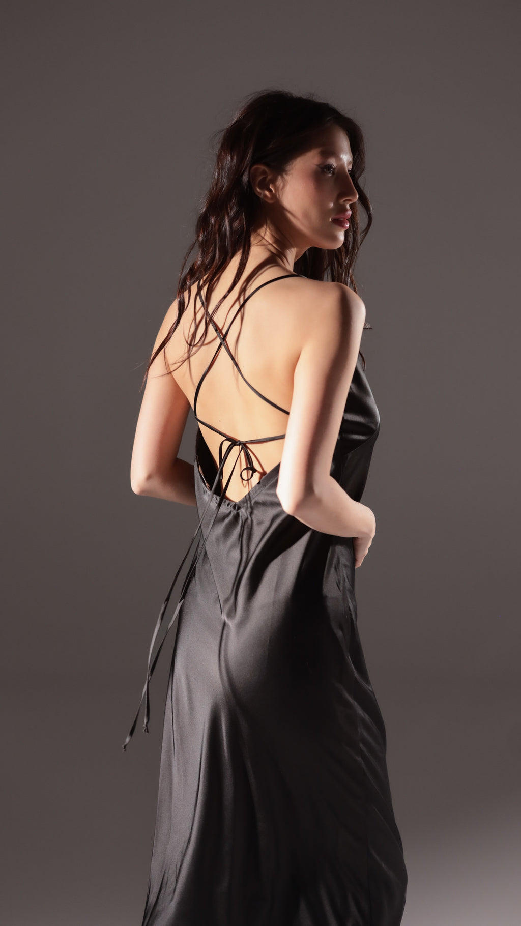 Black slip dress for an alt bride, back view showing criss-cross straps tied at a low open back. Infinity Slip Black by Ephemeris