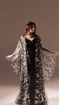 Long black slip dress under a black and white star tulle robe, model with arms outstretched in soft light, Infinity Slip Black