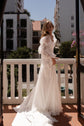 Bride on a sunny balcony wearing sheer organza bridal sleeves on the shoulder over a long chiffon gown, LUNA Sleeves