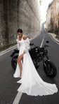 Chiffon wedding dress with a square neck, front slit and long train, crinkled organza sleeves, bride by a motorbike on a canyon road. LUNA by Ephemeris