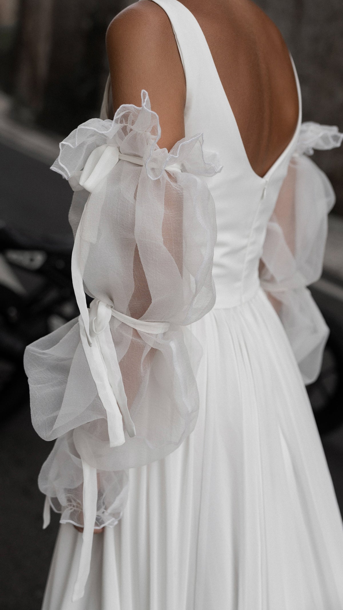 Back detail of a scoop back and zip on a chiffon wedding dress with sheer crinkled organza sleeves tied with ribbons, LUNA