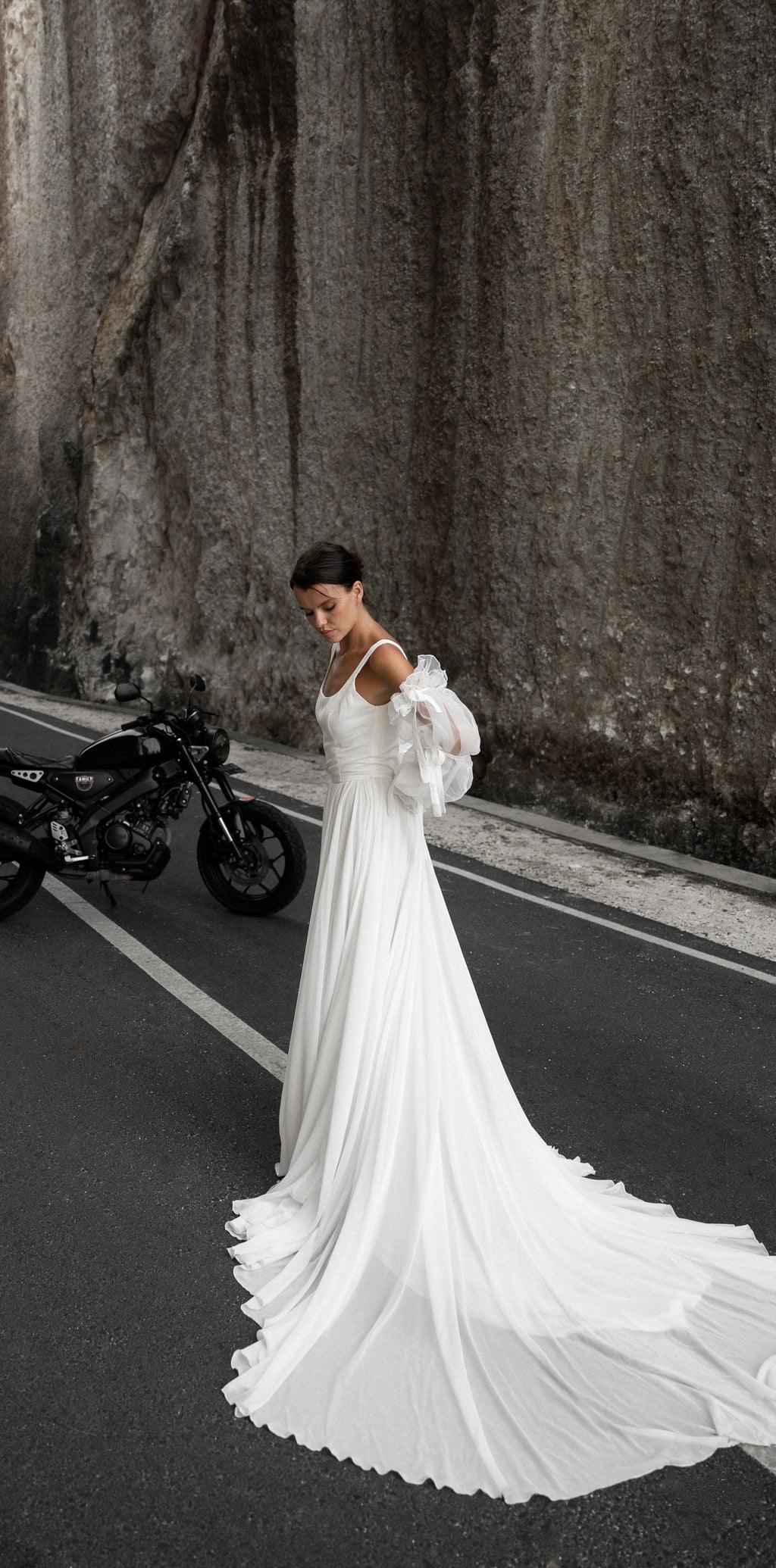 Bride looking down on an empty canyon road, square-neck chiffon wedding dress with a cathedral-length train and organza sleeves, LUNA
