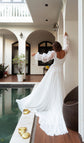 Back view of a scoop-back chiffon wedding dress with ribboned organza sleeves and a long train by a courtyard pool, LUNA