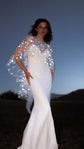 Bride with a hand on her hip at twilight, reflective stars on a high-neck ivory bridal cape caught by flash, Lunar Eclipse Cape Ivory