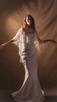 Model with arms out in warm studio light, sheer star bridal cape draping over a corset bodice and mermaid skirt, Lunar Eclipse Cape Ivory