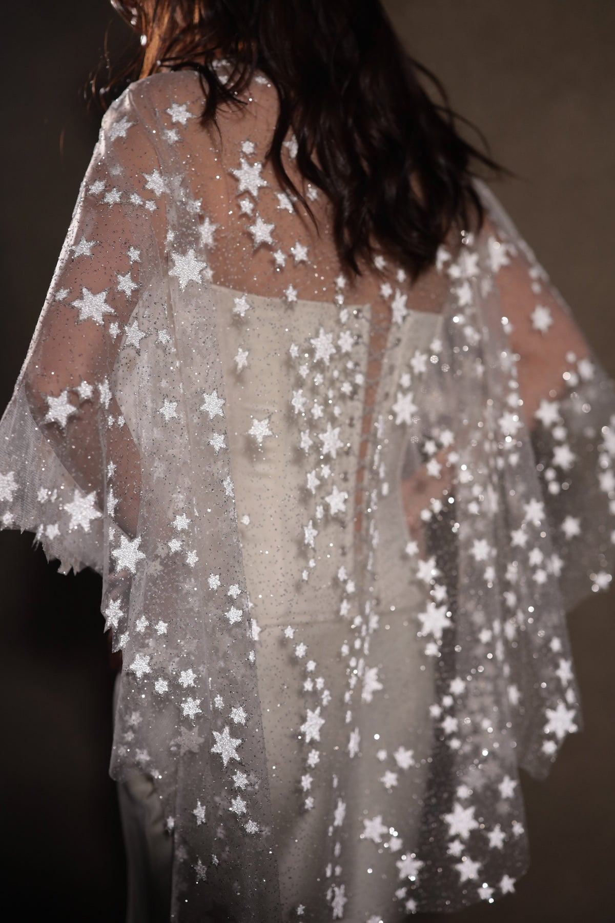 Back crop of a star-scattered bridal cape with scalloped edges falling over a buttoned bodice, low light, Lunar Eclipse Cape Ivory