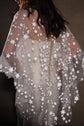 Back crop of a star-scattered bridal cape with scalloped edges falling over a buttoned bodice, low light, Lunar Eclipse Cape Ivory