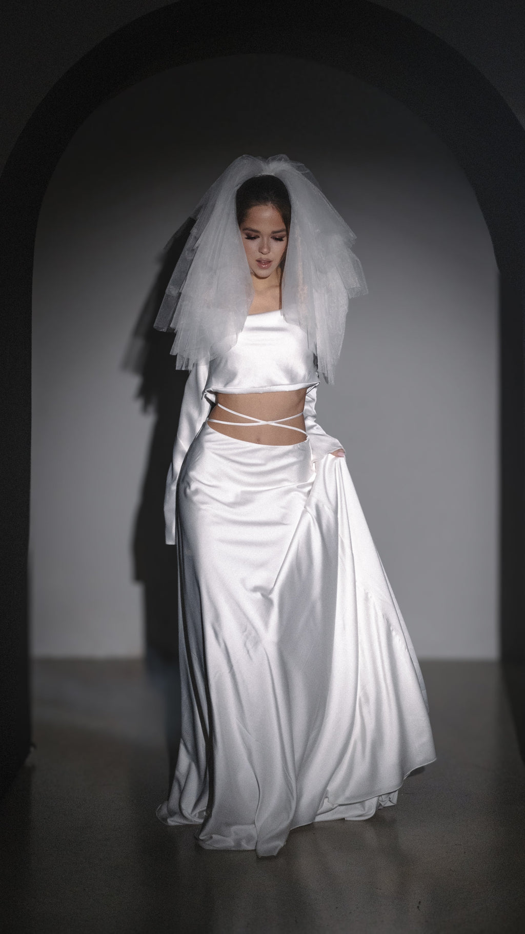 Shoulder-length two-tier wedding veil in soft white tulle with a blusher, worn with a satin crop top and skirt. Madonna Veil by Ephemeris