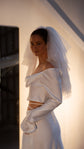 Side view of a short layered wedding veil standing out from the head, off-shoulder satin crop top and long satin gloves, Madonna Veil