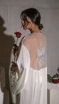 Bride looking over her shoulder holding a red rose, sheer back and embroidered butterfly of an ivory bridal robe, Metamorphosis Robe