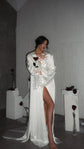 Full-length ivory bridal robe with a front slit and train, star cuffs shining in flash among roses on plinths, Metamorphosis Robe