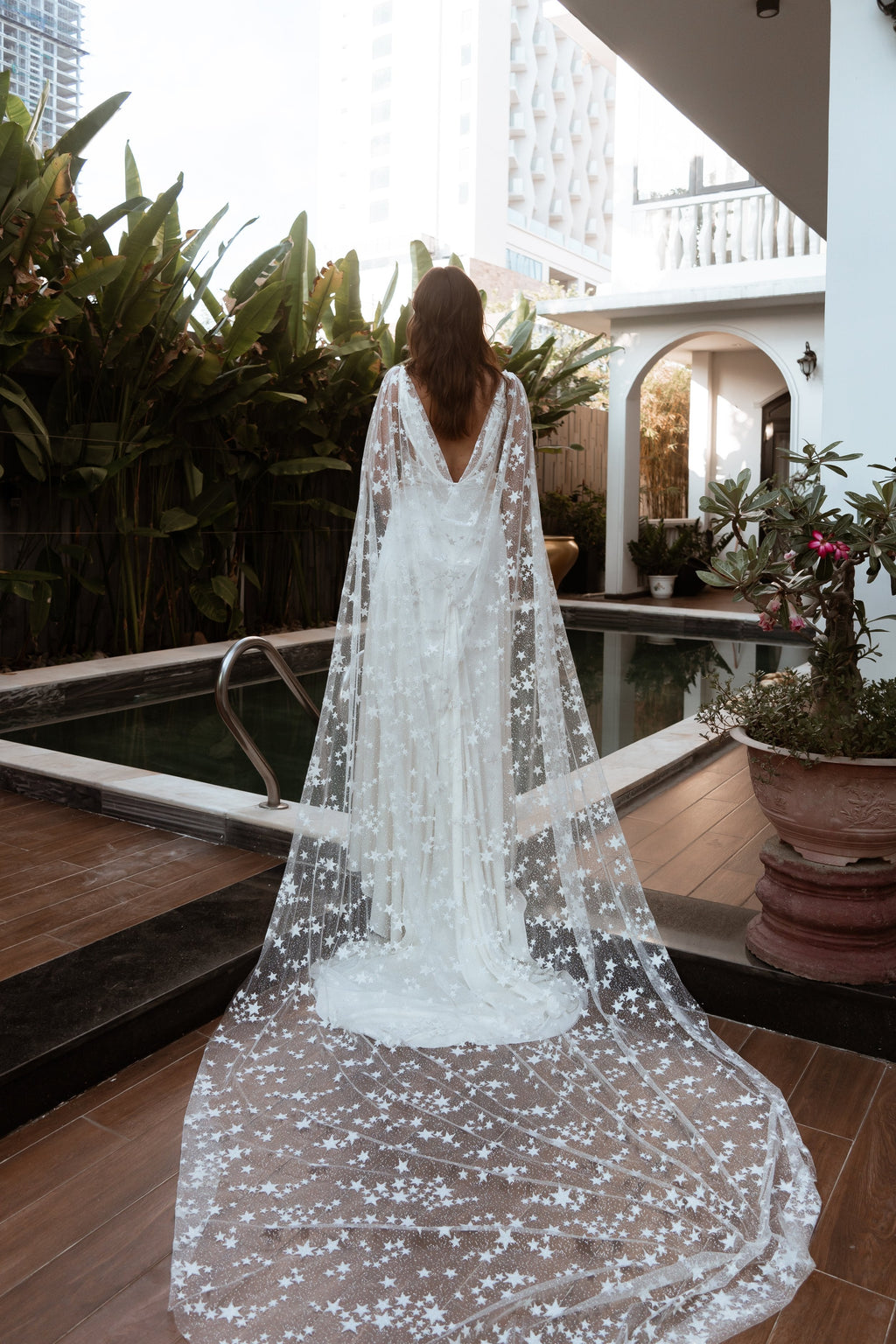 Full-length star bridal cape with a long train behind a bride beside a tropical pool, Milky Way Cape Black