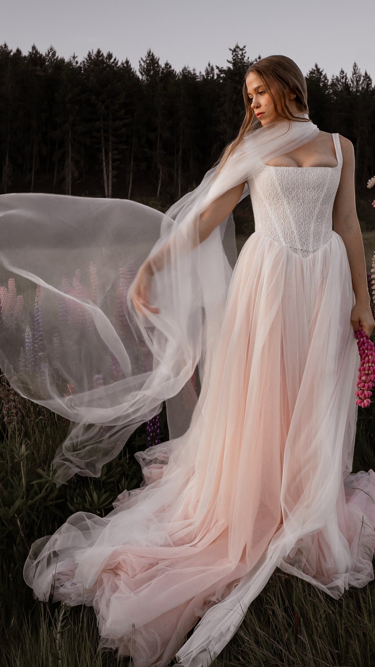 Moonglade super organza veil worn as a bridal neck scarf, floating in the wind in a lupine field at dusk