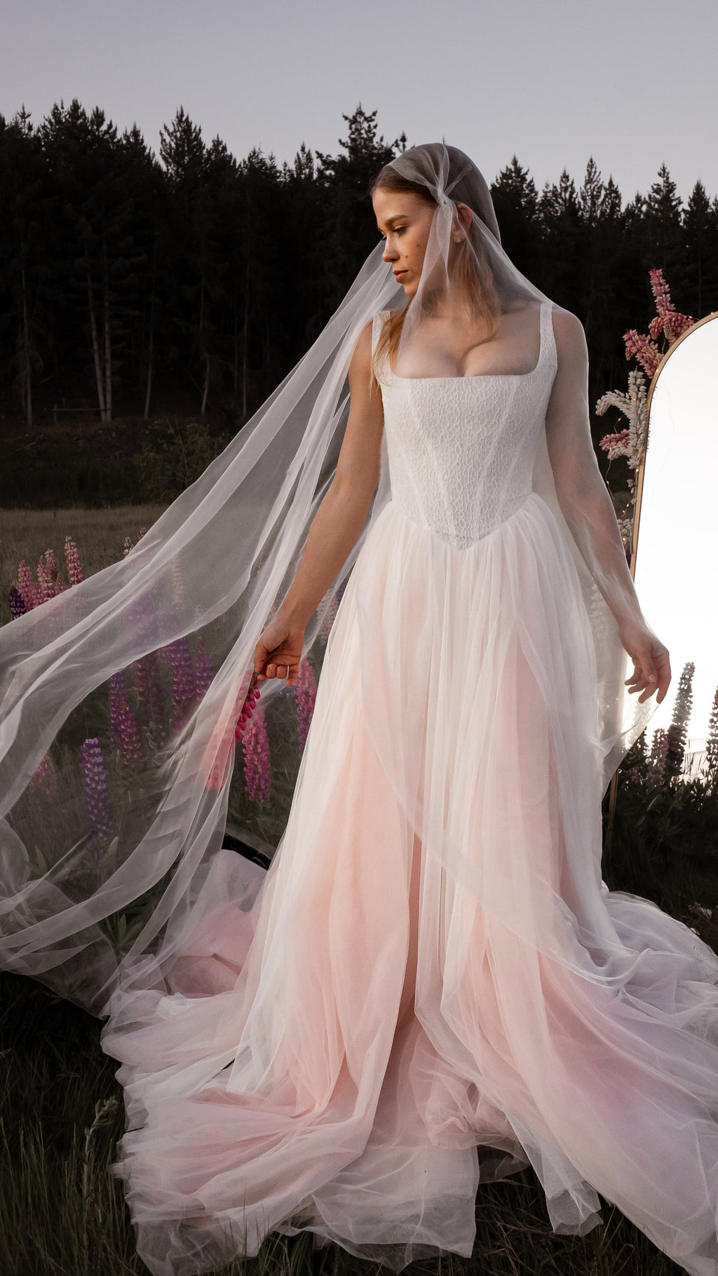 Mantilla-style super organza veil draped over the head and shoulders, outdoor bridal portrait with lupines, Moonglade
